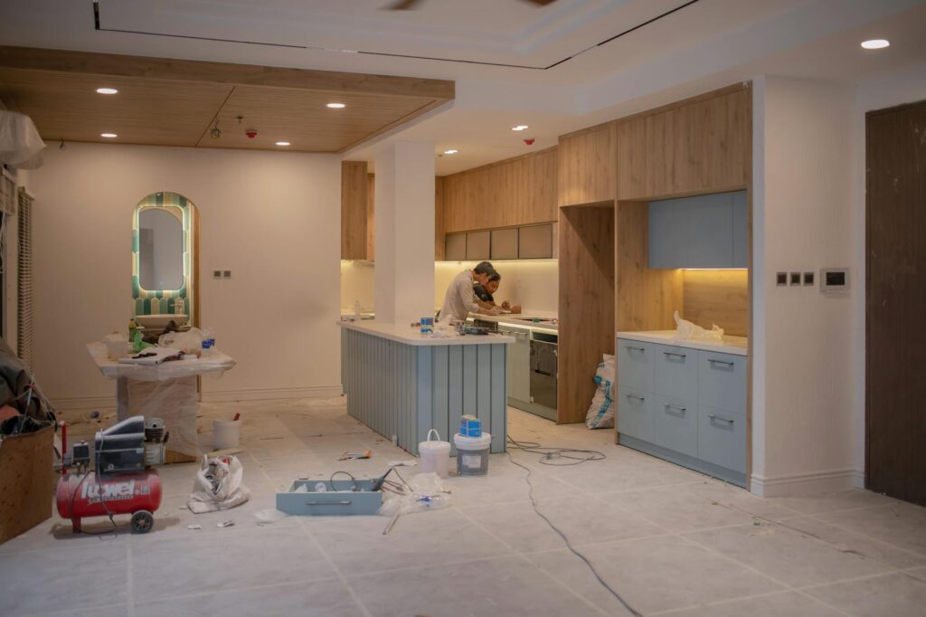 A modern kitchen undergoing renovation, featuring a worker, tools, and materials.